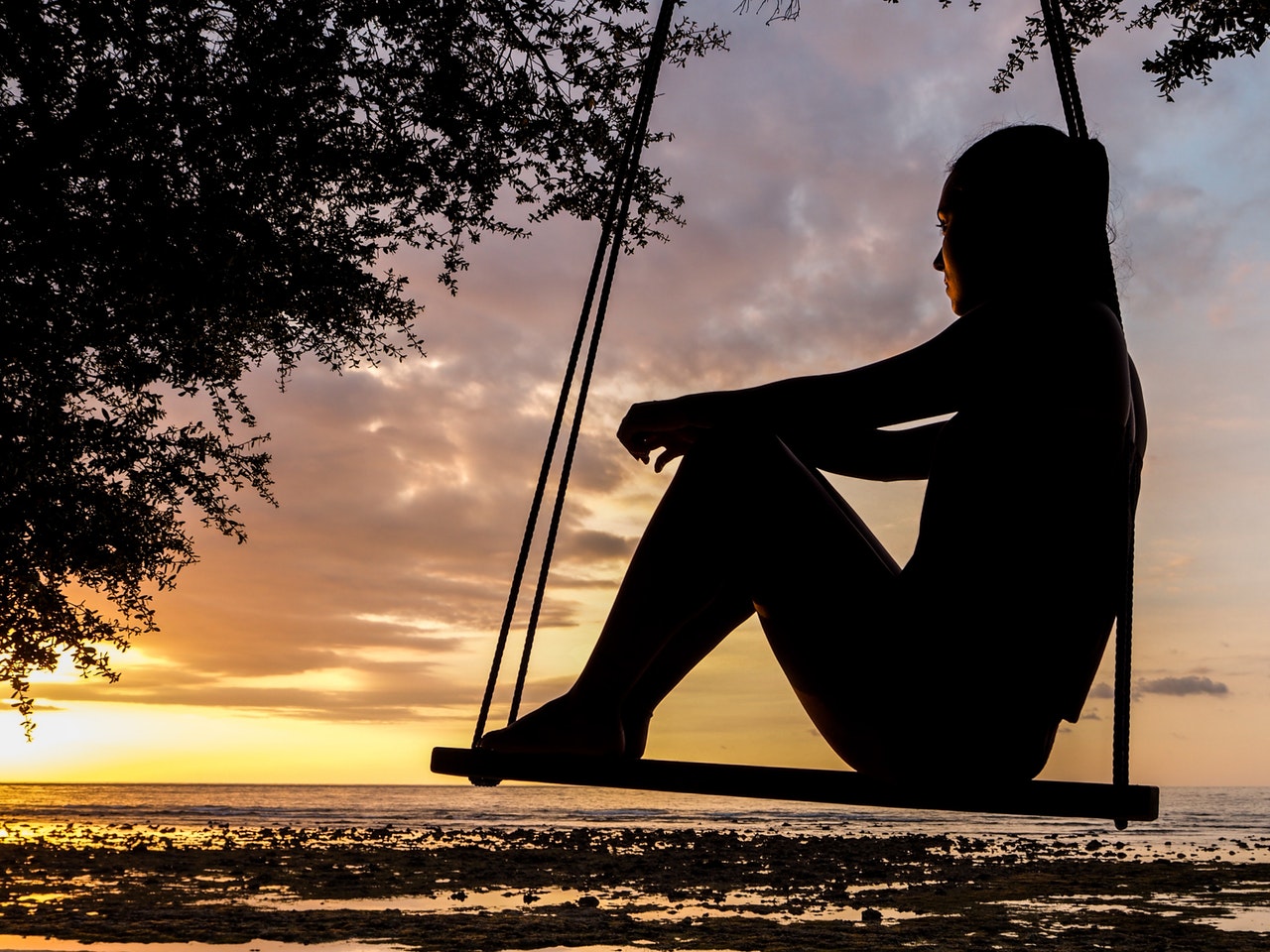 woman_sitting_on_swing_sunset